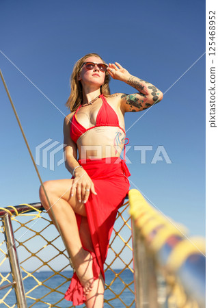 Confident woman in red swimsuit posing on yacht in Turkey sea 125468952