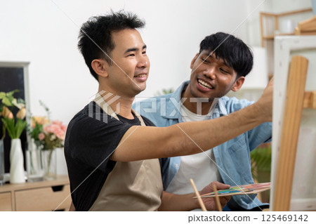 Couple and Artistic Collaboration. A gay couple painting together, showcasing their bond and creativity in a cozy setting. Couple and Artistic Collaboration. A gay couple painting together, showcasing their bond and creativity in a cozy setting. 125469142