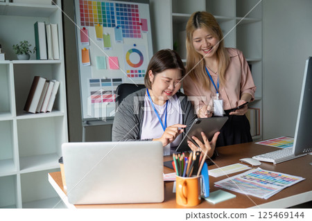 Dynamic graphic design team collaborating on projects with digital devices in a colorful studio 125469144