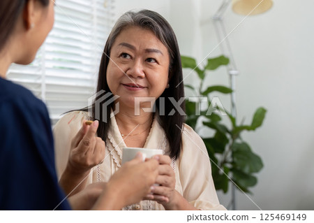 Elderly Wellness and Caregiver Interaction. A caregiver listens as a senior patient discusses her medication, ensuring understanding. Elderly Wellness and Caregiver Interaction. A caregiver listens as a senior patient discusses her medication, ensuring understanding. 125469149