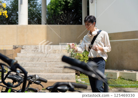 Bicycle Usage and Smartphone Technology. A person navigating a bike parking area, seeking an available bicycle. Bicycle Usage and Smartphone Technology. A person navigating a bike parking area, seeking an available bicycle. 125469330
