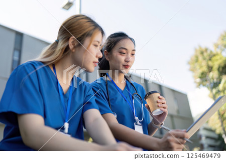 Nurses discussing patient care while enjoying coffee during a break Nurses discussing patient care while enjoying coffee during a break 125469479