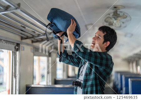 Preparation and Journey. A young traveler organizing his backpack inside a train. Preparation and Journey. A young traveler organizing his backpack inside a train. 125469635