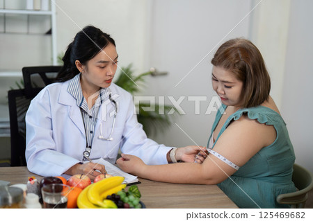 Health Monitoring and Nutrition Tracking. A nutritionist measuring a client's arm during a dietary consultation, emphasizing health monitoring for a personalized nutrition plan. Health Monitoring and Nutrition Tracking. A nutritionist measuring a client's arm during a dietary consultation, emphasizing health monitoring for a personalized nutrition plan. 125469682