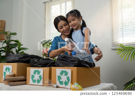 Recycling and Family Engagement. A mother guiding her daughter through a fun recycling task at home. 125469690