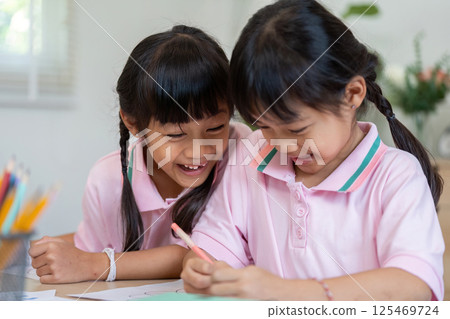 Joy and Learning. Two girls enjoying a fun moment while coloring together. 125469724