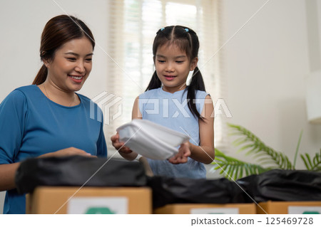 Family Eco-consciousness and Recyclable Materials. A mother smiling while helping her daughter learn about sorting waste. 125469728