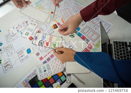 Team Coordination and Idea Exchange. Designers sharing layouts and feedback in an interactive session for UI design. 125469758