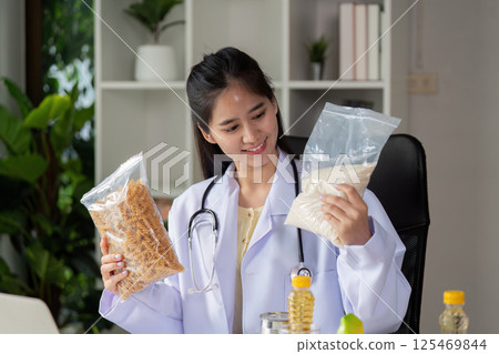 Nutritionist comparing whole grain pasta and rice, promoting healthy eating choices during a virtual consultation. Nutritionist comparing whole grain pasta and rice, promoting healthy eating choices during a virtual consultation. 125469844