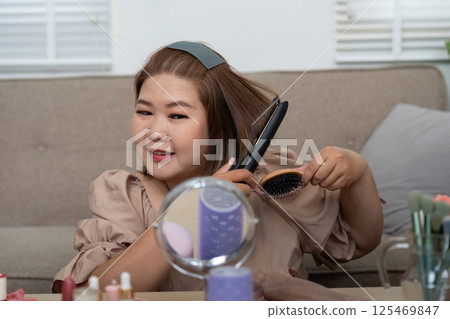 Beauty and Grooming. A woman smoothly brushing her hair while showcasing her beauty routine with joy. Beauty and Grooming. A woman smoothly brushing her hair while showcasing her beauty routine with joy. 125469847