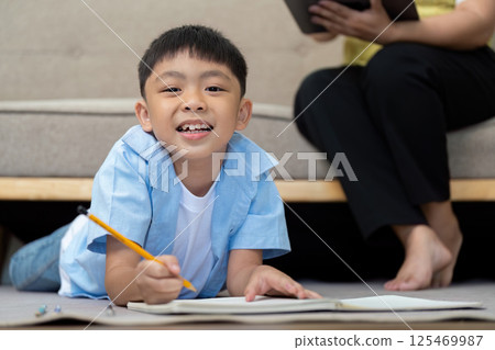 Back to School and Smiles. A cheerful boy smiling while writing in his notebook, enjoying his study time. 125469987