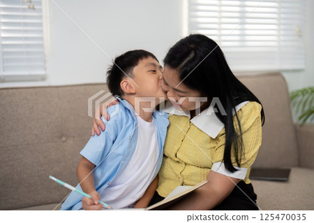 Back to School and Affectionate Moments. A mother and son sharing a loving kiss during study time. 125470035