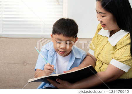 Back to School and Learning Together. A mother helps her son with his homework, fostering a love for learning. 125470040