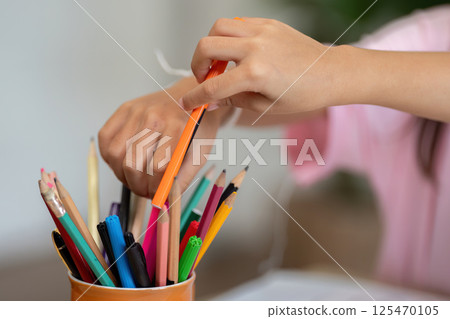 Art Supplies and Creativity. A child organizing colorful pens and pencils in a classroom. 125470105