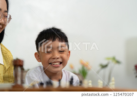 Activity mother and son smiling during chess game Activity mother and son smiling during chess game 125470107