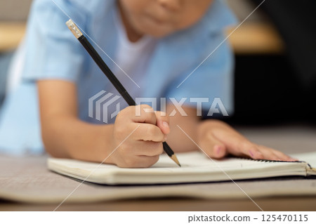 Back to School and Learning. A young boy writing in his notebook, preparing for the school year ahead. 125470115