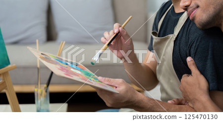 Couple and Artistic Bond. A gay couple collaborating on a colorful painting, showcasing their love and creativity. 125470130