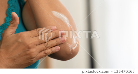 Beauty and Wellness. A senior woman applying lotion on her elbow for skin nourishment. Beauty and Wellness. A senior woman applying lotion on her elbow for skin nourishment. 125470163
