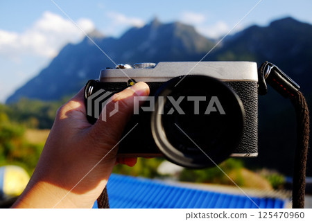 Hand holding vintage mirrorless camera with blue sky on valley Doi Luang Chiang Dao mountain view in Chiang Mai Province of Thailand Hand holding vintage mirrorless camera with blue sky on valley Doi Luang Chiang Dao mountain view in Chiang Mai Province of Thailand 125470960