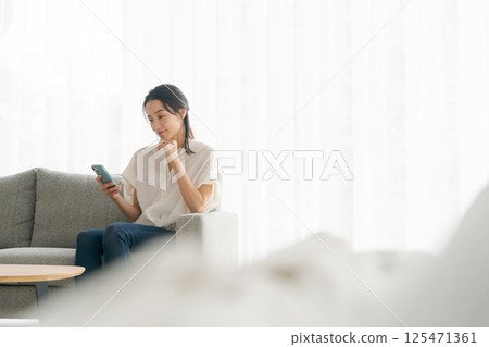 一個女人坐在沙發上和放鬆 一個女人坐在沙發上和放鬆 125471361