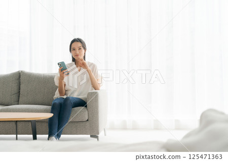 一個女人坐在沙發上和放鬆 一個女人坐在沙發上和放鬆 125471363
