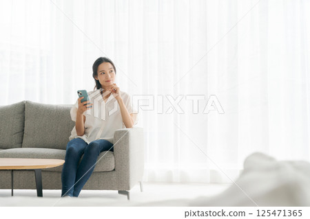 A woman sitting on a sofa and relaxing A woman sitting on a sofa and relaxing 125471365