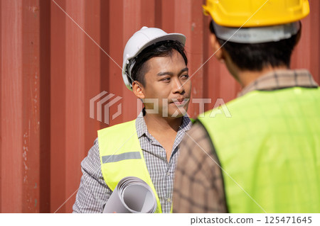 Project Coordination. Young engineers collaborating on logistics in a construction setting. 125471645