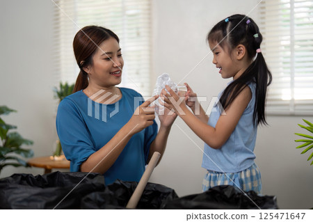 Sustainability and Family Bonding. A mother and daughter engaging in recycling activities at home, teaching eco-friendly habits. 125471647