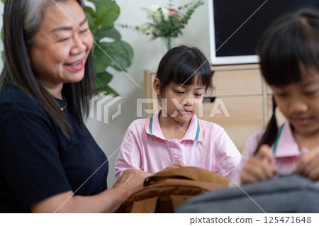 Family Time and School Preparation. An adult assisting children with their school bags. 125471648
