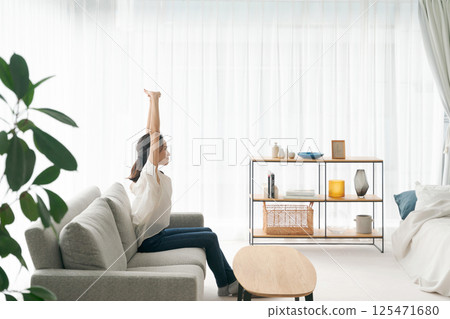 一個女人坐在沙發上和放鬆 一個女人坐在沙發上和放鬆 125471680