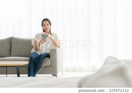 A woman sitting on a sofa and relaxing A woman sitting on a sofa and relaxing 125472132