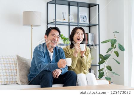 Middle-aged couple drinking coffee in the living room Middle-aged couple drinking coffee in the living room 125473082