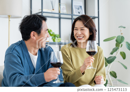 Middle-aged couple drinking wine in the living room Middle-aged couple drinking wine in the living room 125473113