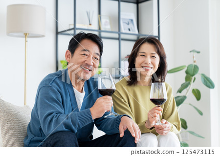 Middle-aged couple drinking wine in the living room Middle-aged couple drinking wine in the living room 125473115