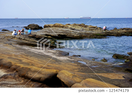 People playing on the rocks at Kannonzaki Park and boats passing through the Uraga Channel 125474179