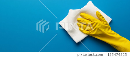 Cleaning Surface with Yellow Glove and White Cloth on Blue Background 125474225