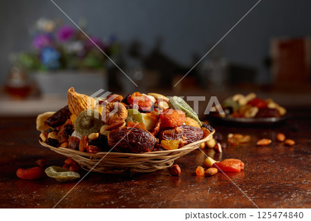 Dried tropical fruits, nuts, and raisins on a kitchen table. 125474840