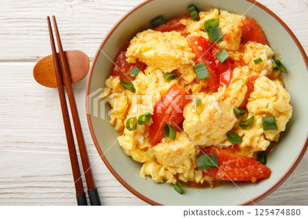 Stir-fried tomato and scrambled eggs is a common dish in China closeup on the plate. Horizontal top view 125474880