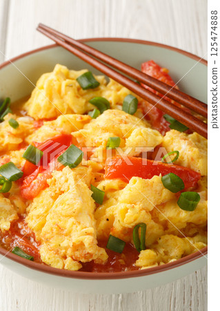 Chinese Tomato Egg Stir Fry with green onions closeup on the plate. Vertical 125474888