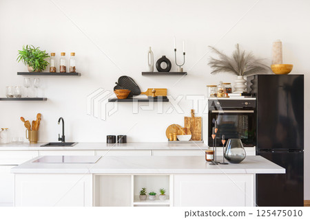 Kitchen interior with countertop and black water tap on white wall background with wooden shelves Kitchen interior with countertop and black water tap on white wall background with wooden shelves 125475010
