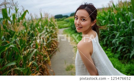 A Japanese woman living in the countryside looking back in a summer corn field 125476652