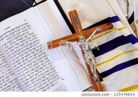 24 April 2025 Jerusalem Israel Messianic Jewish Congregation is Crucifix rests on top of sacred scripture Hebrew Tanakh prayer shawl during reflective devotional moment. "Hebrew Tanakh prayer holy 125476654
