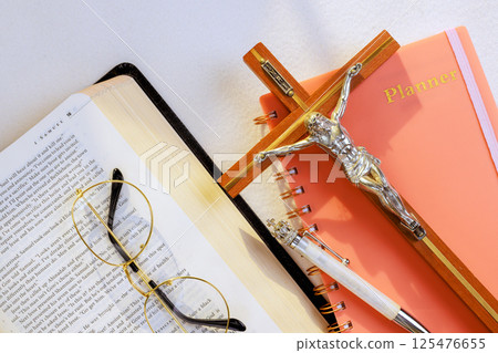 24 April 2025 Vatican City Italy Planner, open Bible, crucifix, glasses are neatly arranged for reflection, reading holy book 125476655