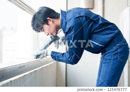 Male worker applying caulking material during exterior construction work Male worker applying caulking material during exterior construction work 125476777