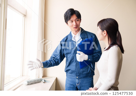 A woman asking a repairman to repair her house 125477530
