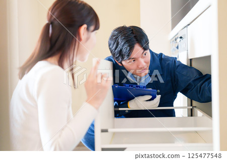 A woman asking a repairman to repair her house 125477548