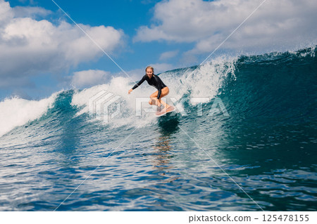 Woman surfer on crashing wave on a sunny day, surfing in ocean. 125478155