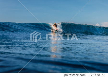 Woman surfer on perfect wave, surfing in ocean. 125478158