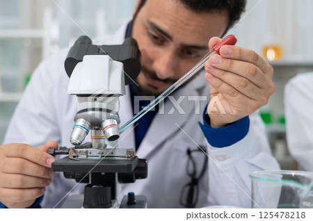 Male scientist dropping chemical liquid on slide at microscope. Science and Technology concept Male scientist dropping chemical liquid on slide at microscope. Science and Technology concept 125478218
