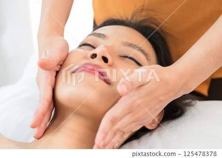 Face massage. Young woman enjoying spa facial massage treatment at spa salon Face massage. Young woman enjoying spa facial massage treatment at spa salon 125478378